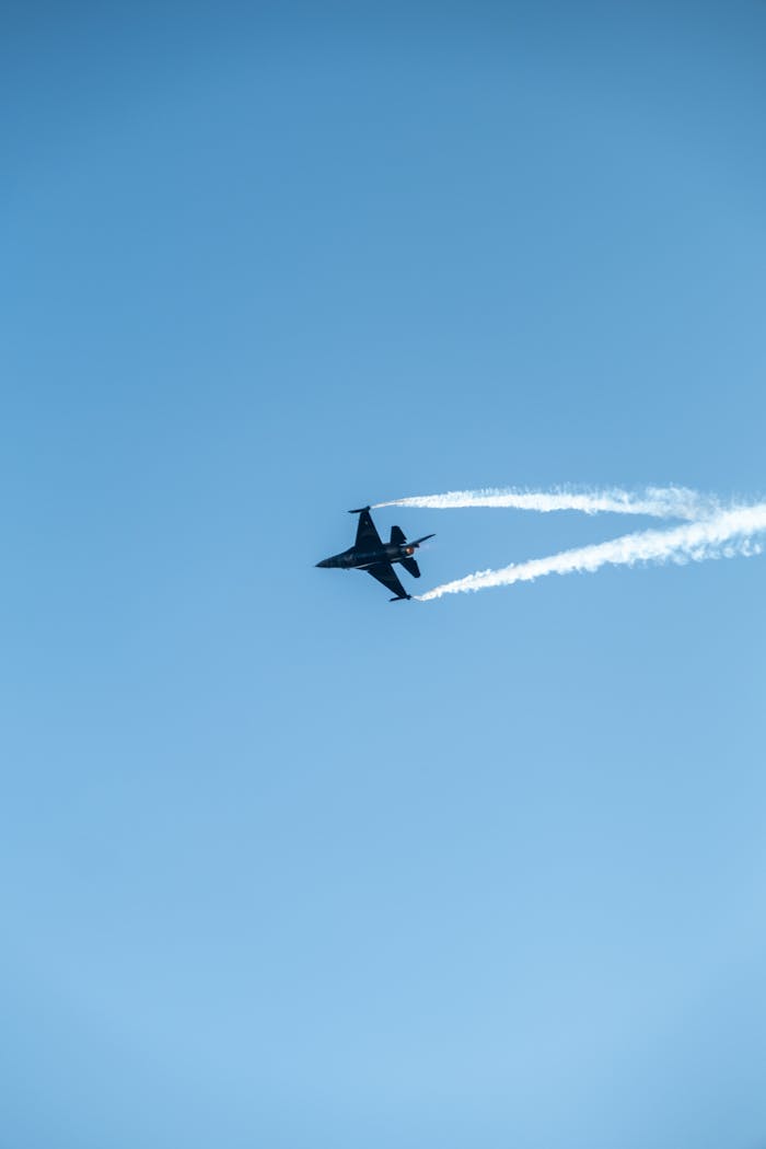 gallery-1 Jet fighter flying with contrails in a bright blue sky.
